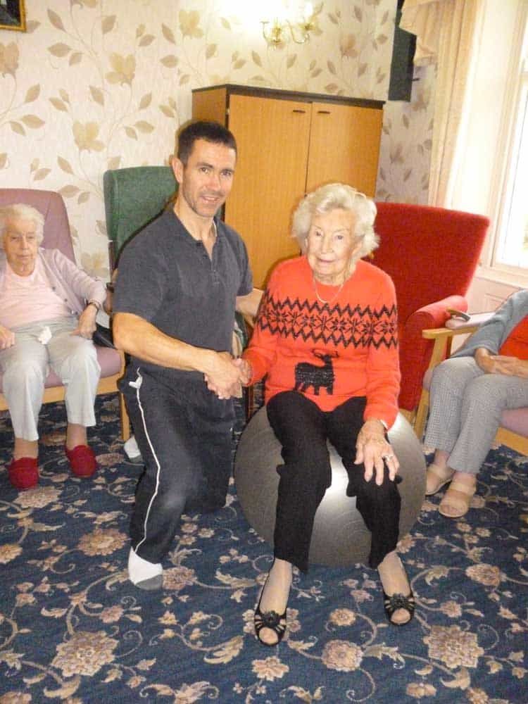 Older lady sat on a medicine ball having physiotherapy by Andy Gamble